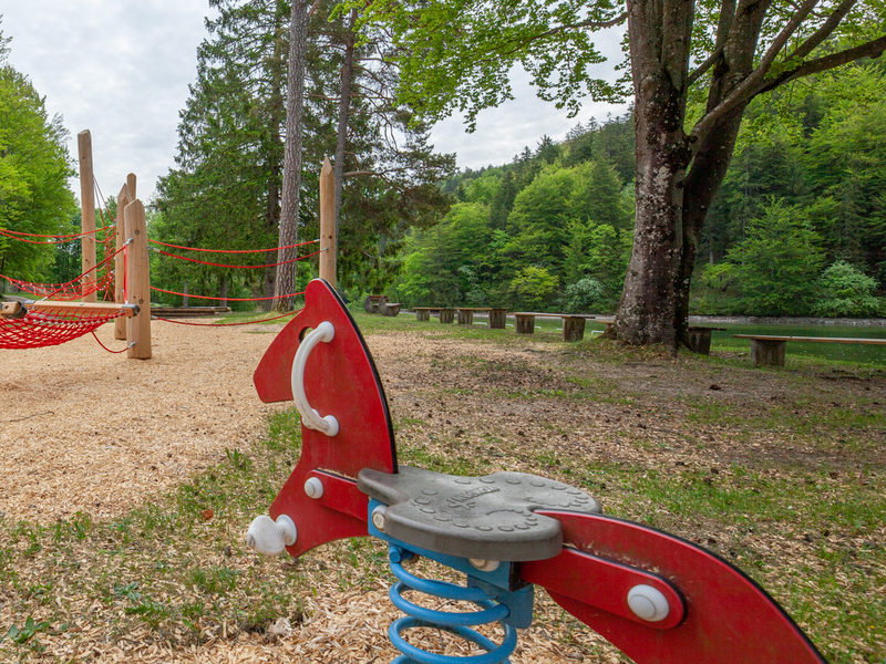 Ein Schaukelpferd beim Spielplatz Oberseebad. Im Hintergrund eine Nestschaukel.