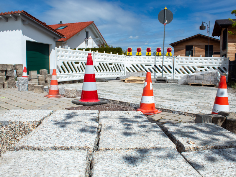 Im Vordergrund ist ein Stapel Granitsteine zu sehen. Im Hintergrund eine halbfertige Fläche bereits verlegter Steine